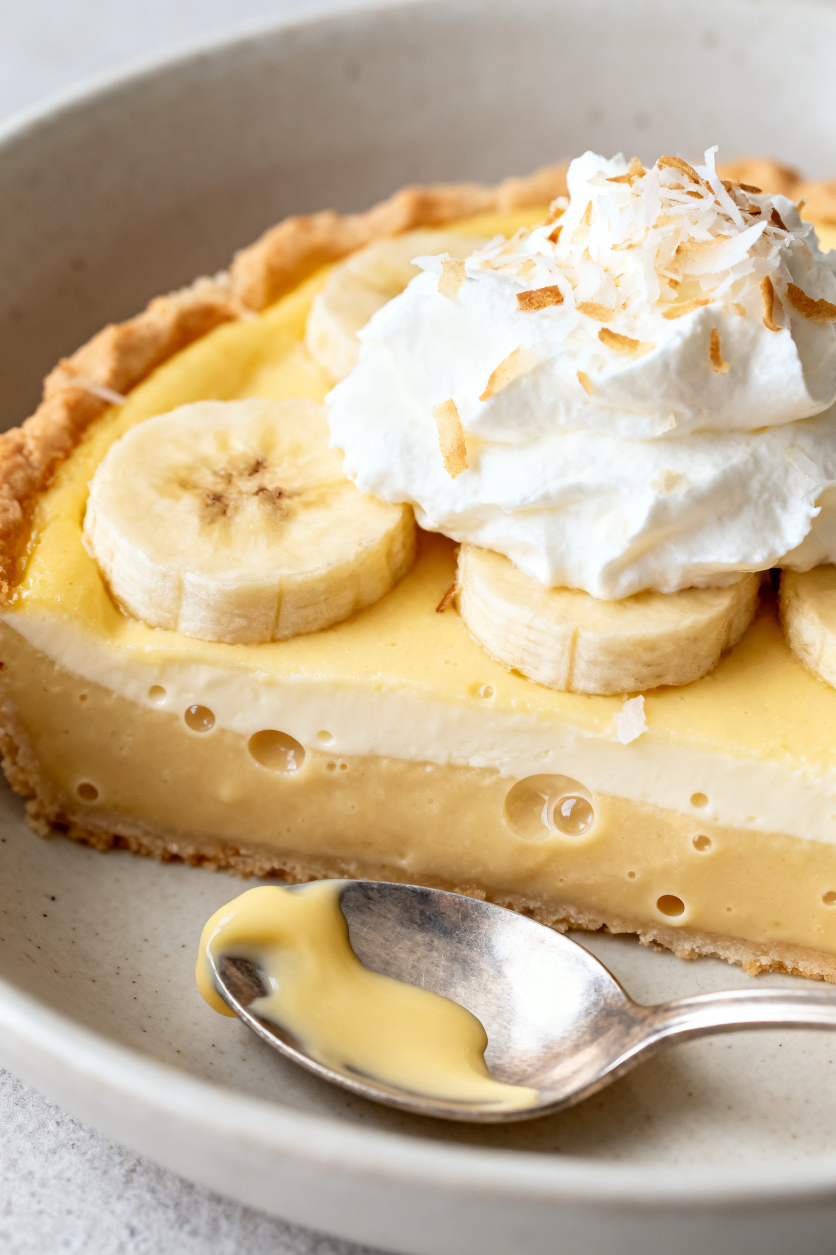 Close-up detail of a warm, spooned serving of Banana Custard Bake in a shallow bowl: silky custard l