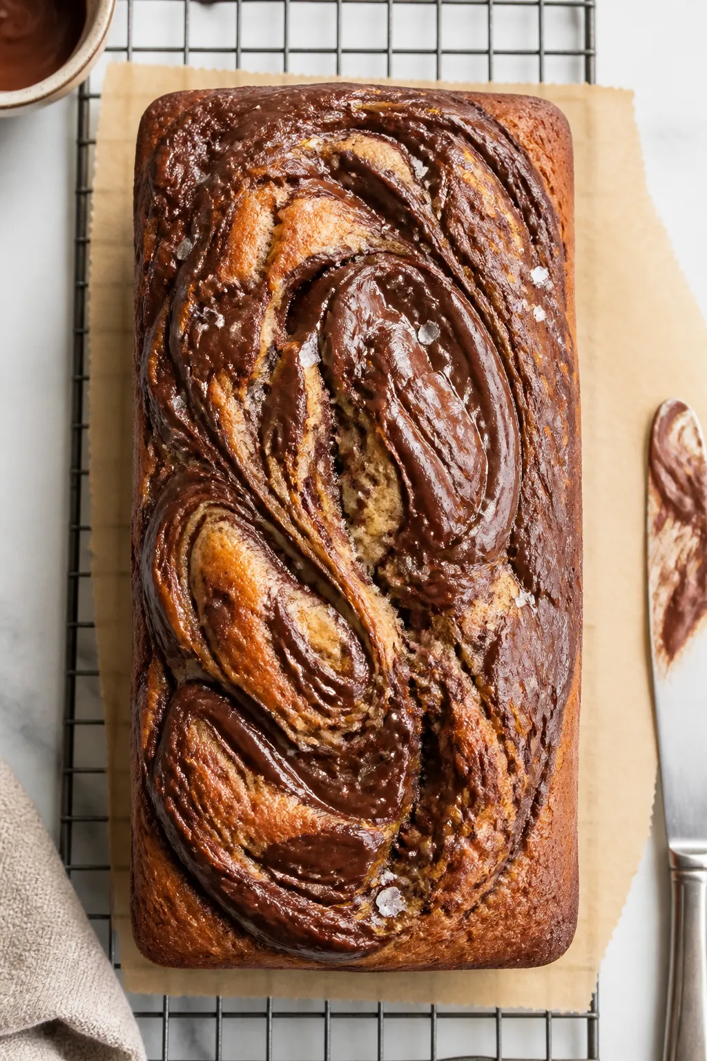 Overhead shot of a freshly baked Banana Bread Dessert with Nutella Swirl cooling on a wire rack, loa